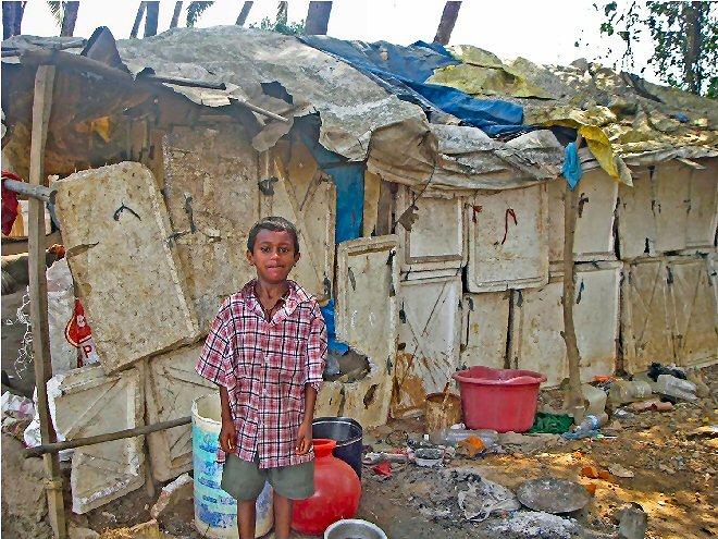 Boy outside his Indian slum home